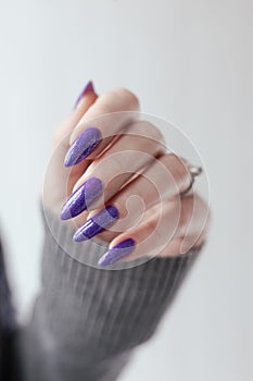 Female hand with purple lilac manicure holds a bottle of nail polish