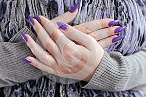 Female hand with purple lilac manicure holds a bottle of nail polish