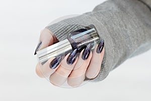 Female hand with purple lilac manicure holds a bottle of nail polish