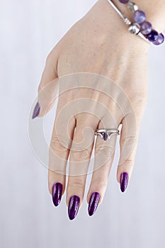 Female hand with purple lilac manicure holds a bottle of nail polish