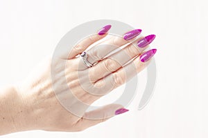 Female hand with purple lilac manicure holds a bottle of nail polish