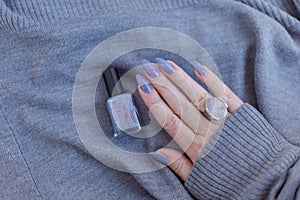 Female hand with purple lilac manicure holds a bottle of nail polish