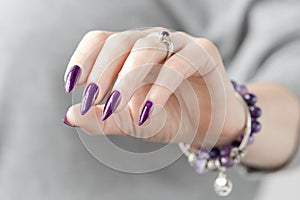 Female hand with purple lilac manicure holds a bottle of nail polish