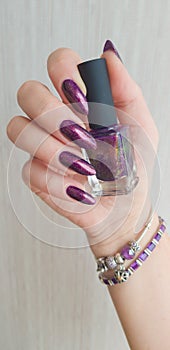Una mujer mano púrpura largo tiempo a esmalte de unas una botella 