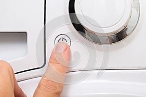 Female hand pushing start stop button of washer, washing machine cycle interraption or starting, beginning