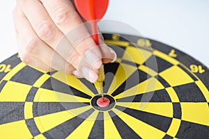 Female hand put red dart arrow right in center of dartboard, hit goal or put new aim