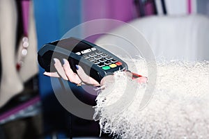 Female hand puts bankcard into reader on defocused background. Payment with credit card. EDC machine or credit card photo