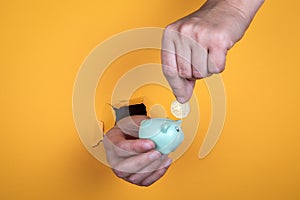 Female hand puts a coin into a piggy bank. Savings, profits, studies and home loan concept
