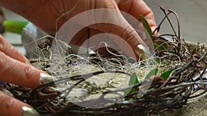 Female hand puts sisal and green twigs in the easter nest.