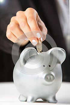 Female hand putting coin in piggy bank