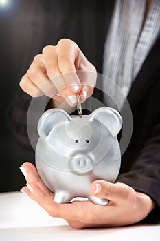 Female hand putting coin in piggy bank