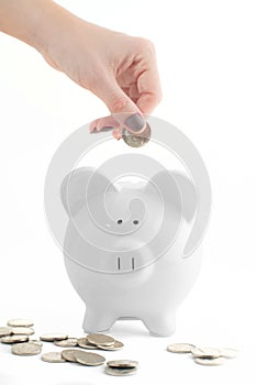 Female hand putting coin into piggy bank isolated on white