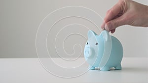 Female hand putting coin into piggy bank. Saving money for future use