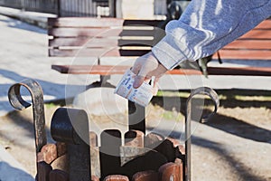 Female hand putting disposable paper cup in to trash bin. Environmental protection concept. Blurred background. Selective focus