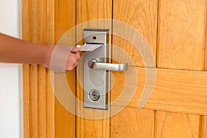 Female hand putting and holding magnetic key card switch in to open hotel room door