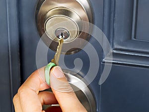 Female hand putting house key into door lock