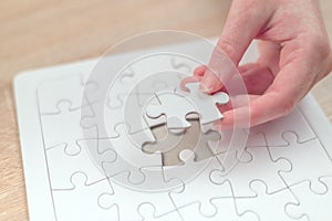 Female hand putting a missing piece into jigsaw puzzle