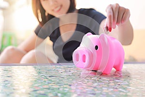 Female hand putting money into piggy bank.