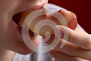 female hand putting a piece of ripe peach in the mouth, healthy food dessert