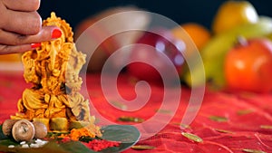 Female hand putting a red Tika on the forehead of Lord Ganesha during a Pooja ceremony