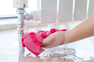 Female hand with rag cleaning water from heating radiator leak