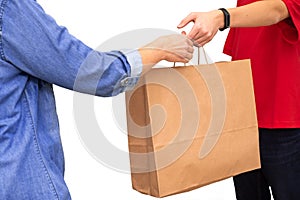 Female hand receiving package from delivery man. Delivery courier holding brown paper bag isolated on white background