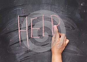 Female hand with red chalk writes help on a black chalk board