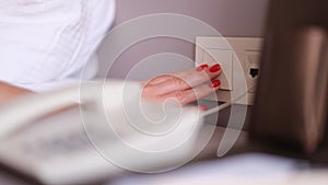 Female hand with red manicure turning off light with white switch closeup