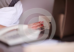 Female hand with red manicure turning off light with white switch closeup