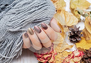 Female hand with red nail design. Golden autunm nail design. Woman hands hold grey wool shawl