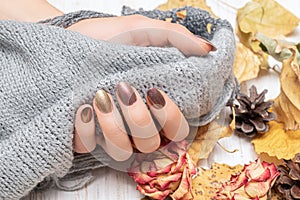 Female hand with red nail design. Golden autunm nail design. Woman hands hold grey wool shawl