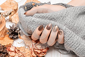 Female hand with red nail design. Golden autunm nail design. Woman hands hold grey wool shawl