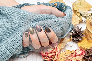 Female hand with red nail design. Golden autunm nail design. Woman hands hold grey wool shawl