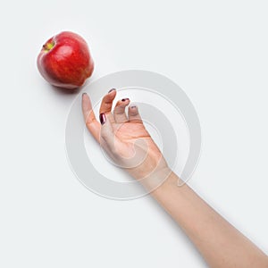 Female hand with red nails dropped red apple