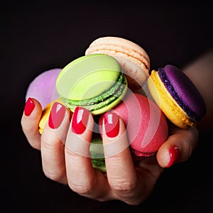 Female hand with red nails holding macarons