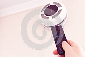Female hand by remote control turning on recuperator for fresh indoor air quality photo