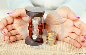 Female hand's with hourglass and coin. photo