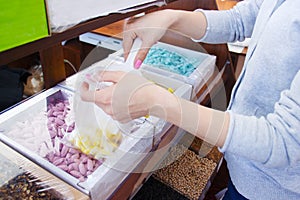 Female hand with a scoop is picking up yellow candy from a cardboard box. details of candy at the candy shop