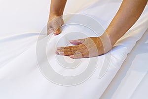 Female Hand set up white bed sheet in bedroom or maid hands making bed in a hotel room