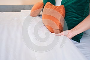 Female Hand set up white bed sheet in bedroom or maid hands making bed in a hotel room