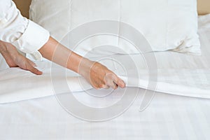 Female Hand set up white bed sheet in room hotel