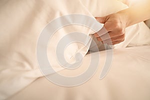 Female Hand set up white bed sheet in room hotel