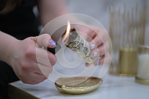 Female hand sets fire to incense on a copper bowl. Aroma therapy, to relax after a hard day. Smells for concentration
