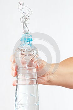 Female hand shaking bottle of water with a splash