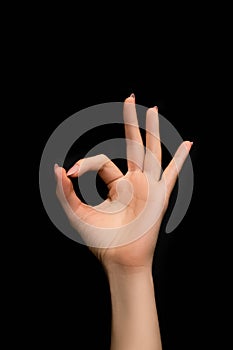 Female hand show OK sign on black background. Female hand with perfect manicure sho OK sign. Ok gesture on black background