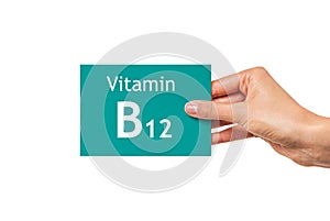 Female hand shows a card with the inscription Vitamin B12. Vitamin B12.
