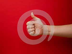 Female hand shows thumb up gesture on a background