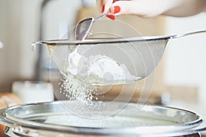 Female hand sift flour through sieve