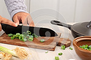 Female Hand SLicing Green Onion on Wooden Choppingboard