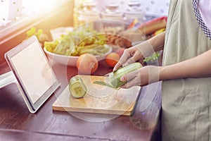 Female hand slicing green vegetable, prepare ingredients for cooking follow cooking online video clip on website via tablet.